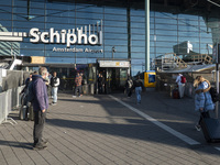 Entrance of Amsterdam Airport Schiphol AMS EHAM airport terminal with passenger and flight crew walking by and the logo inscription over the...