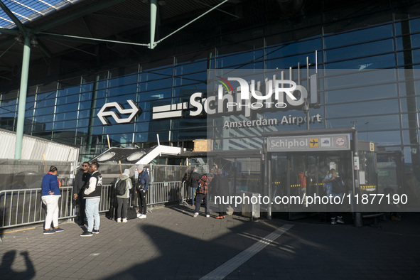 Entrance of Amsterdam Airport Schiphol AMS EHAM airport terminal with passenger and flight crew walking by and the logo inscription over the...