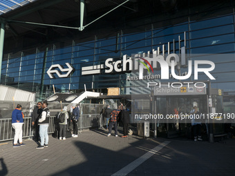 Entrance of Amsterdam Airport Schiphol AMS EHAM airport terminal with passenger and flight crew walking by and the logo inscription over the...