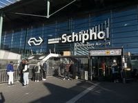 Entrance of Amsterdam Airport Schiphol AMS EHAM airport terminal with passenger and flight crew walking by and the logo inscription over the...