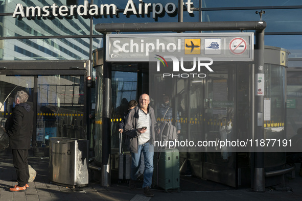 Entrance of Amsterdam Airport Schiphol AMS EHAM airport terminal with passenger and flight crew walking by and the logo inscription over the...