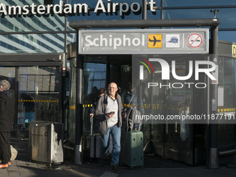 Entrance of Amsterdam Airport Schiphol AMS EHAM airport terminal with passenger and flight crew walking by and the logo inscription over the...