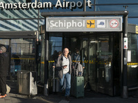 Entrance of Amsterdam Airport Schiphol AMS EHAM airport terminal with passenger and flight crew walking by and the logo inscription over the...