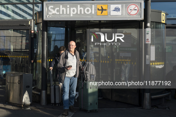 Entrance of Amsterdam Airport Schiphol AMS EHAM airport terminal with passenger and flight crew walking by and the logo inscription over the...