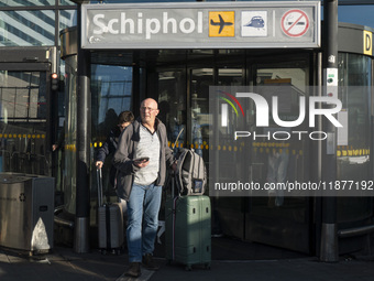 Entrance of Amsterdam Airport Schiphol AMS EHAM airport terminal with passenger and flight crew walking by and the logo inscription over the...