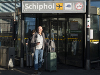 Entrance of Amsterdam Airport Schiphol AMS EHAM airport terminal with passenger and flight crew walking by and the logo inscription over the...