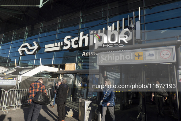 Entrance of Amsterdam Airport Schiphol AMS EHAM airport terminal with passenger and flight crew walking by and the logo inscription over the...