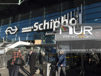 Entrance of Amsterdam Airport Schiphol AMS EHAM airport terminal with passenger and flight crew walking by and the logo inscription over the...