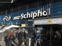 Entrance of Amsterdam Airport Schiphol AMS EHAM airport terminal with passenger and flight crew walking by and the logo inscription over the...