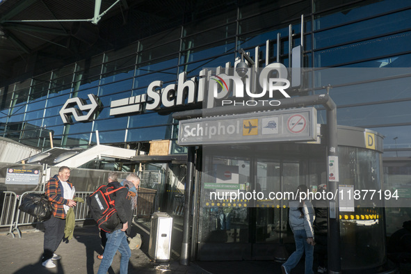 Entrance of Amsterdam Airport Schiphol AMS EHAM airport terminal with passenger and flight crew walking by and the logo inscription over the...