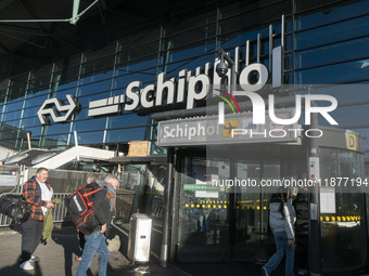 Entrance of Amsterdam Airport Schiphol AMS EHAM airport terminal with passenger and flight crew walking by and the logo inscription over the...