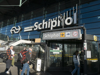 Entrance of Amsterdam Airport Schiphol AMS EHAM airport terminal with passenger and flight crew walking by and the logo inscription over the...