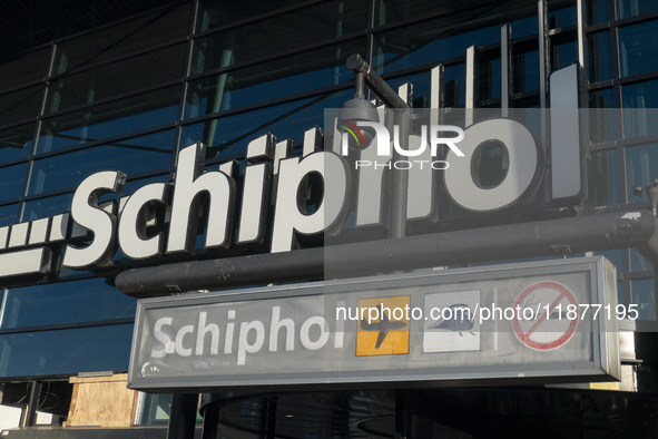 Entrance of Amsterdam Airport Schiphol AMS EHAM airport terminal with passenger and flight crew walking by and the logo inscription over the...