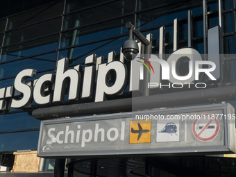 Entrance of Amsterdam Airport Schiphol AMS EHAM airport terminal with passenger and flight crew walking by and the logo inscription over the...