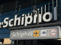 Entrance of Amsterdam Airport Schiphol AMS EHAM airport terminal with passenger and flight crew walking by and the logo inscription over the...