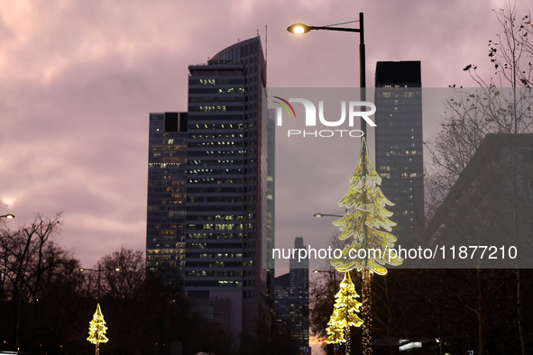 Christmas decorations in the form of glowing Christmas trees hang from street lamps in Warsaw, Poland, on December 12, 2024. 