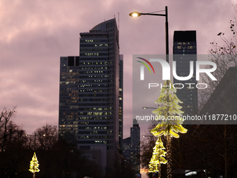 Christmas decorations in the form of glowing Christmas trees hang from street lamps in Warsaw, Poland, on December 12, 2024. (