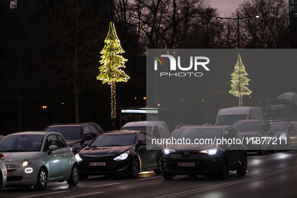 Christmas decorations in the form of glowing Christmas trees hang from street lamps in Warsaw, Poland, on December 12, 2024. 