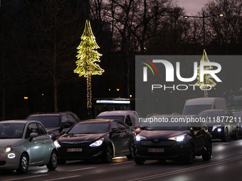 Christmas decorations in the form of glowing Christmas trees hang from street lamps in Warsaw, Poland, on December 12, 2024. (