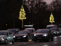 Christmas decorations in the form of glowing Christmas trees hang from street lamps in Warsaw, Poland, on December 12, 2024. (