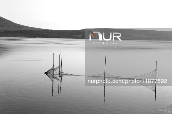 This black and white image shows the reflection of fishing nets on the still waters of a lake, in Varano Lake, Italy, on July 16, 2023. 