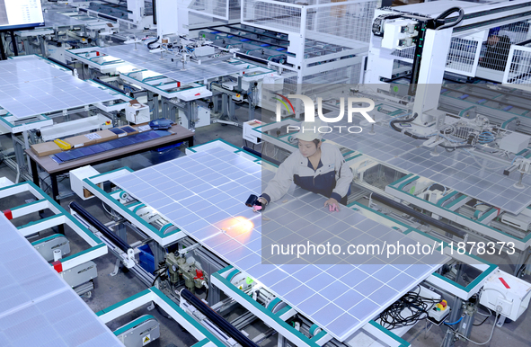 A worker produces solar photovoltaic products at a digital workshop in Suqian, Jiangsu province, China, on December 17, 2024. 