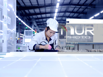 A worker produces solar photovoltaic products at a digital workshop in Suqian, Jiangsu province, China, on December 17, 2024. (