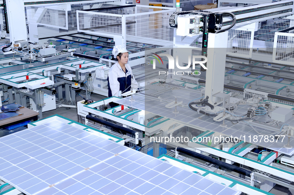 A worker produces solar photovoltaic products at a digital workshop in Suqian, Jiangsu province, China, on December 17, 2024. 