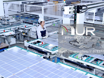 A worker produces solar photovoltaic products at a digital workshop in Suqian, Jiangsu province, China, on December 17, 2024. (