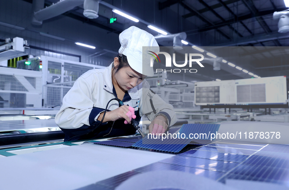 A worker produces solar photovoltaic products at a digital workshop in Suqian, Jiangsu province, China, on December 17, 2024. 