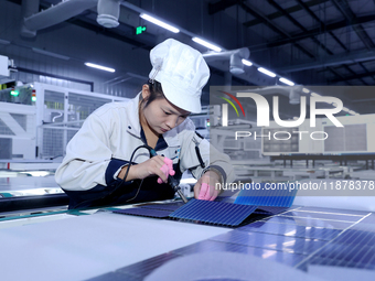 A worker produces solar photovoltaic products at a digital workshop in Suqian, Jiangsu province, China, on December 17, 2024. (