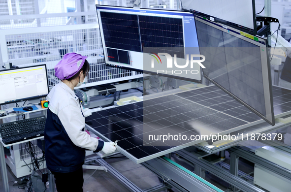 A worker produces solar photovoltaic products at a digital workshop in Suqian, Jiangsu province, China, on December 17, 2024. 