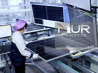 A worker produces solar photovoltaic products at a digital workshop in Suqian, Jiangsu province, China, on December 17, 2024. (