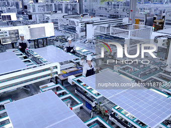 A worker produces solar photovoltaic products at a digital workshop in Suqian, Jiangsu province, China, on December 17, 2024. (