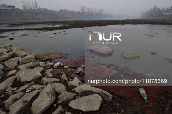 Locals throw used mattresses into the River Jhelum, causing water pollution, as pictured in Sopore, Jammu and Kashmir, India, on December 18...