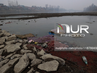 Locals throw used mattresses into the River Jhelum, causing water pollution, as pictured in Sopore, Jammu and Kashmir, India, on December 18...