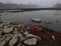 Locals throw used mattresses into the River Jhelum, causing water pollution, as pictured in Sopore, Jammu and Kashmir, India, on December 18...