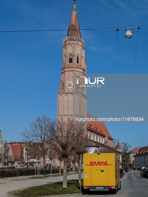 A DHL delivery van parks near a historic church in Landshut, Bavaria, Germany, on March 9, 2024. 