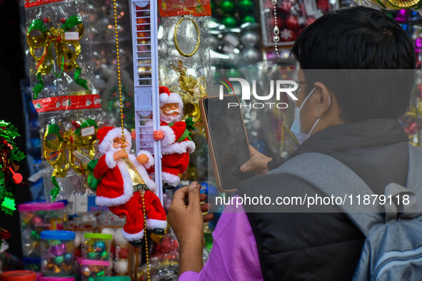 A man takes a picture of a Santa Claus doll at a marketplace ahead of Christmas in Kolkata, India, on December 18, 2024. 