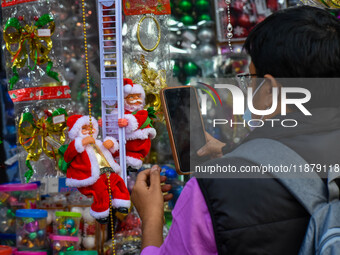 A man takes a picture of a Santa Claus doll at a marketplace ahead of Christmas in Kolkata, India, on December 18, 2024. (