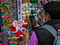 A man takes a picture of a Santa Claus doll at a marketplace ahead of Christmas in Kolkata, India, on December 18, 2024. (