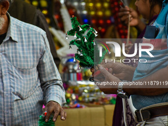 A man shops for a miniature Christmas tree at a marketplace in Kolkata, India, on December 18, 2024. (