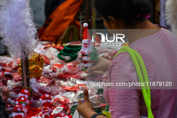 A lady shops for a miniature Santa Claus doll at a marketplace ahead of Christmas in Kolkata, India, on December 18, 2024. 