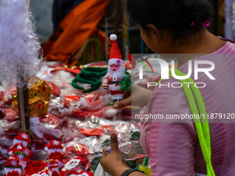 A lady shops for a miniature Santa Claus doll at a marketplace ahead of Christmas in Kolkata, India, on December 18, 2024. (