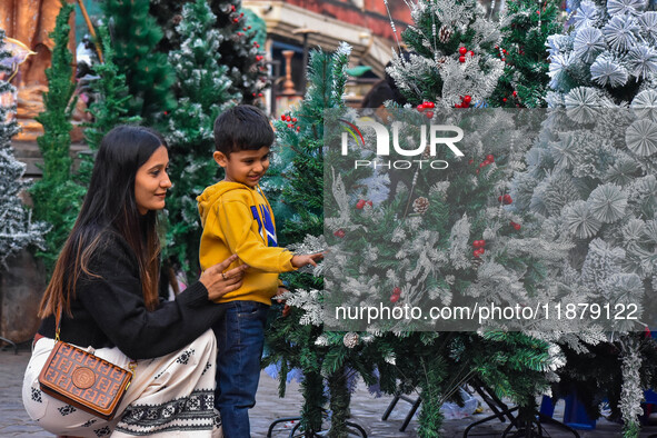 A mother and child check out Christmas trees at a marketplace ahead of Christmas in Kolkata, India, on December 18, 2024. 