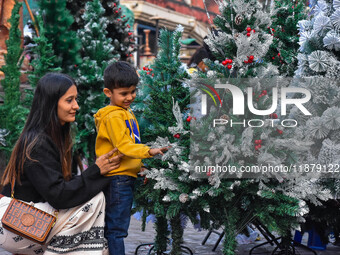 A mother and child check out Christmas trees at a marketplace ahead of Christmas in Kolkata, India, on December 18, 2024. (