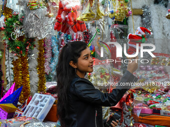 A lady shops for a Santa Claus doll, and a mother and child check out Christmas trees at a marketplace ahead of Christmas in Kolkata, India,...