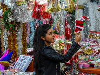 A lady shops for a Santa Claus doll, and a mother and child check out Christmas trees at a marketplace ahead of Christmas in Kolkata, India,...