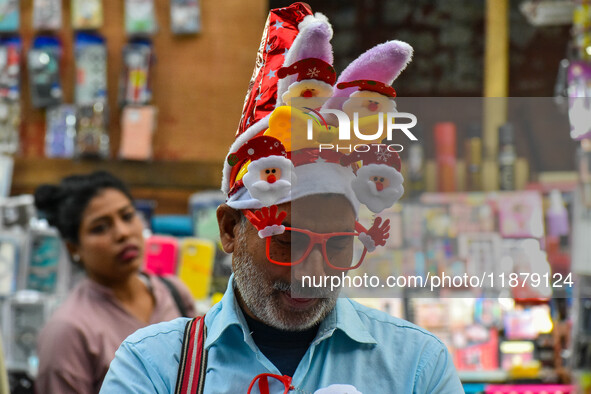 A man sells various souvenirs, and a mother and child check out Christmas trees at a marketplace ahead of Christmas in Kolkata, India, on De...