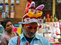 A man sells various souvenirs, and a mother and child check out Christmas trees at a marketplace ahead of Christmas in Kolkata, India, on De...